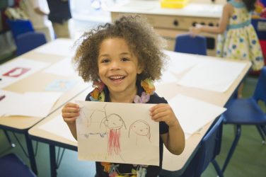 Mixed race boy showing off drawing