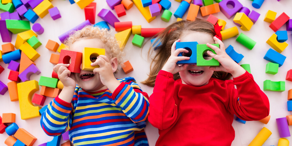 Two kids playing with blocks on the floor