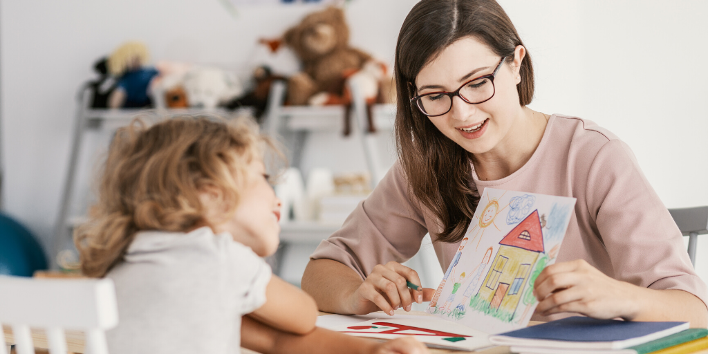 Early years practitioner showing a child a drawing