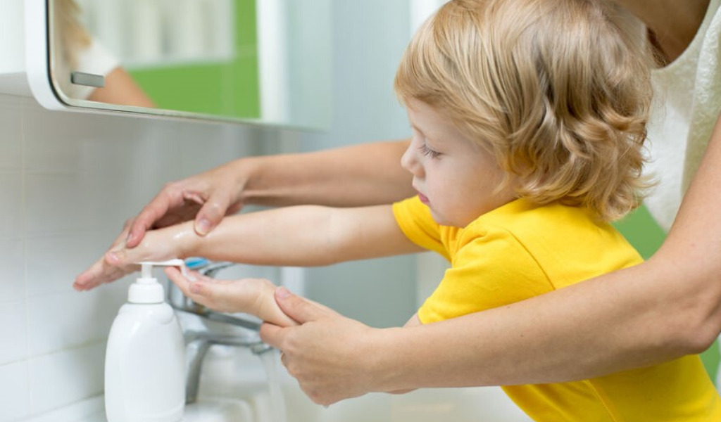 child washing their hands with an adult