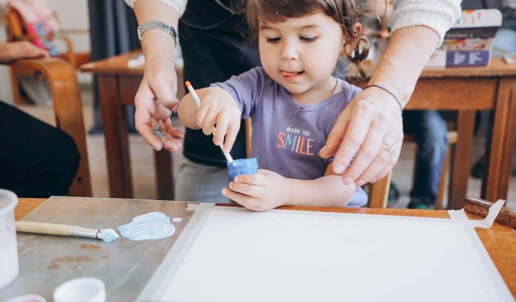 childminder helping a child paint