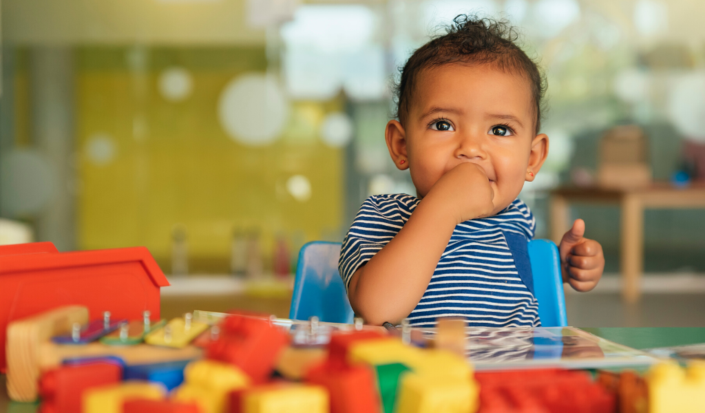 happy baby surrounded by toys at nursery