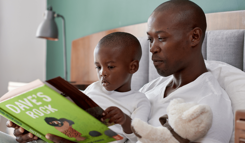 boy reading in bed with dad