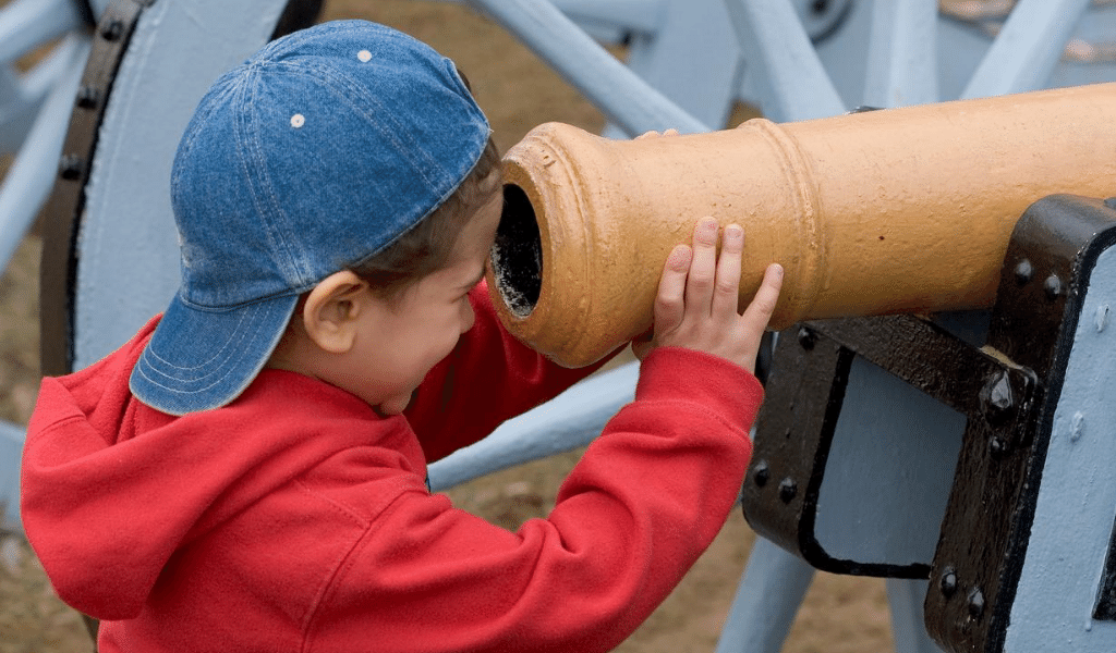 child curious looking through a cannon