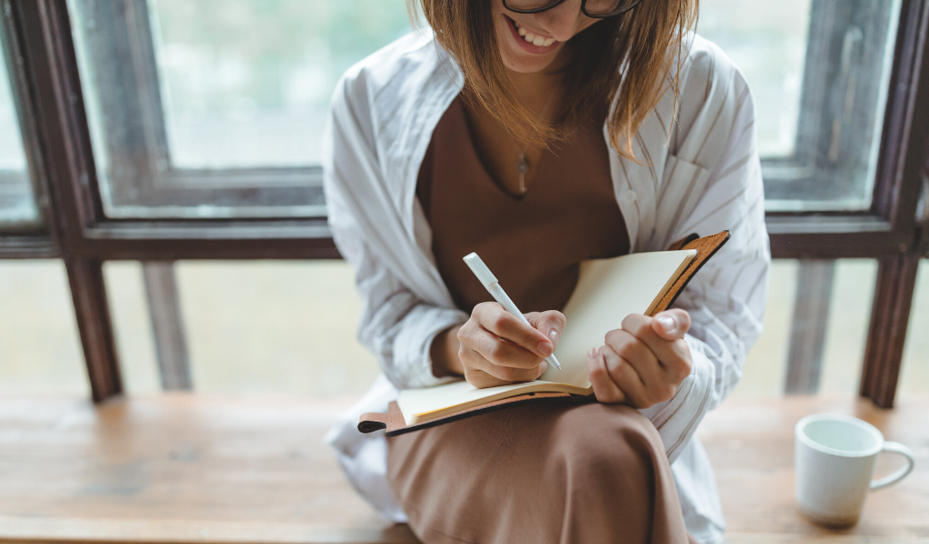 woman writing down notes on a journal