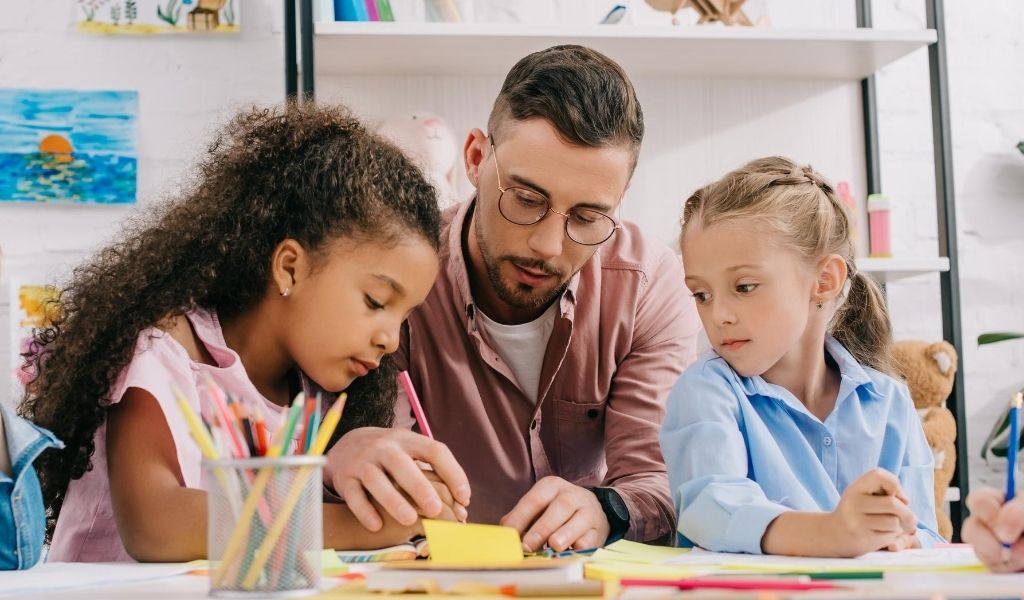 a male childcare practitioner helping two girls