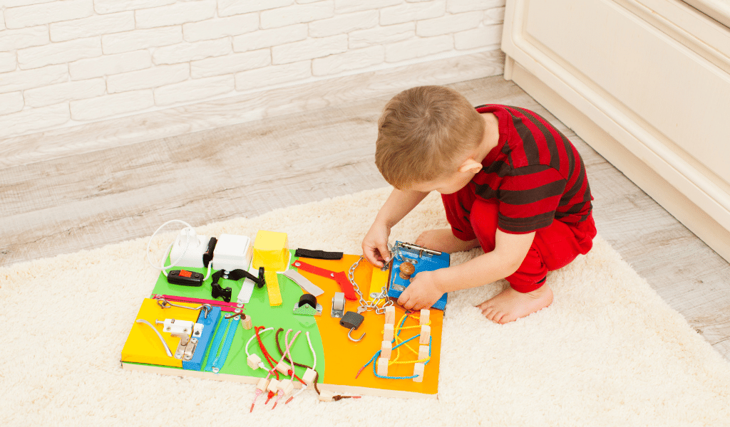 child playing with a sensory board on the floor