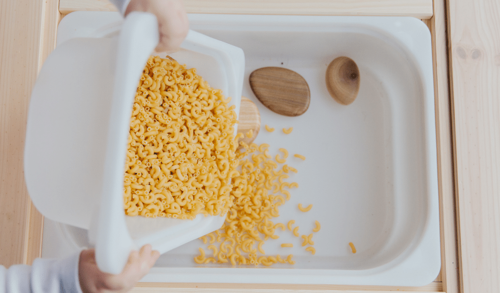 child playing with pasta in a box