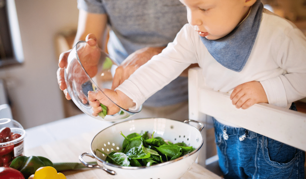 dad helping a child prepare a salad