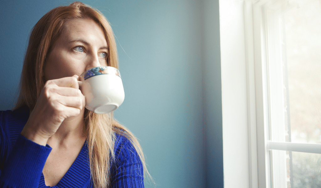 Childminder sipping tea decompressing while looking out of the window