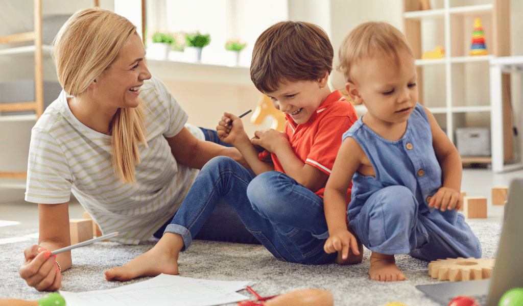 woman playing with children on the floor and children are happy and relaxed