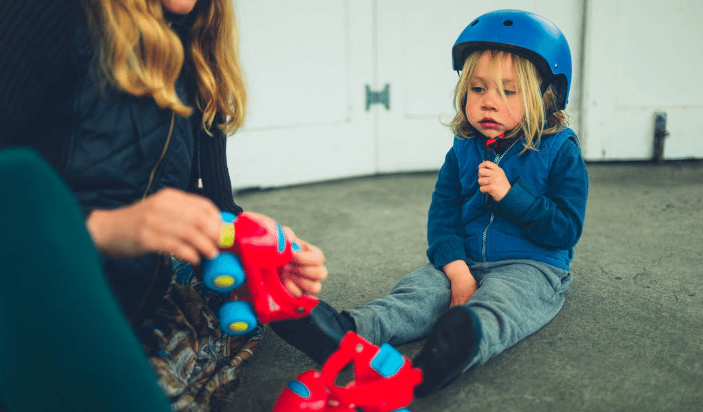 woman helping a child wear roller skates