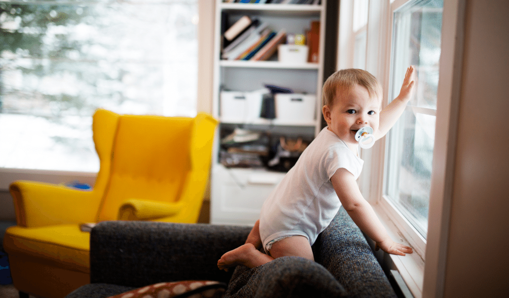 toddler standing on sofa looking out of the window