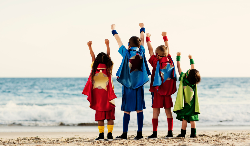 children dressed as super heroes on a beach