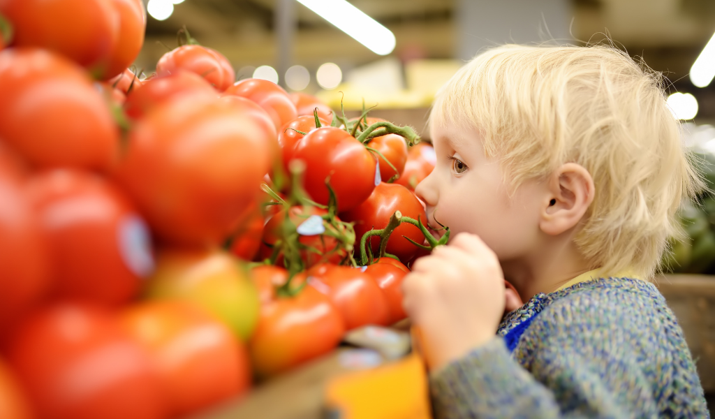 blond hair boy smelling tomatoes