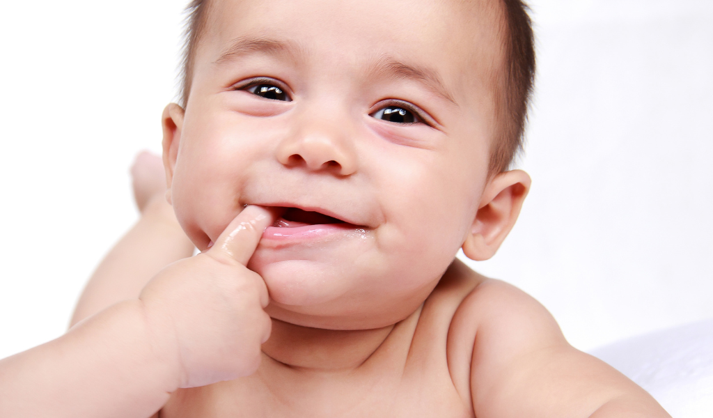 Baby with finger in his mouth smiling