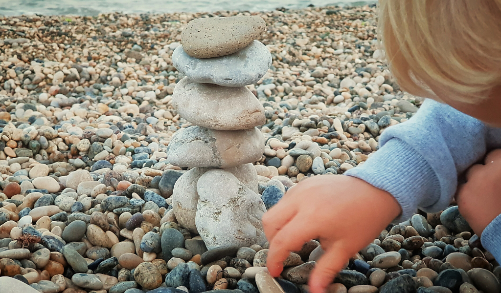 Child sorting pebbles on a beach