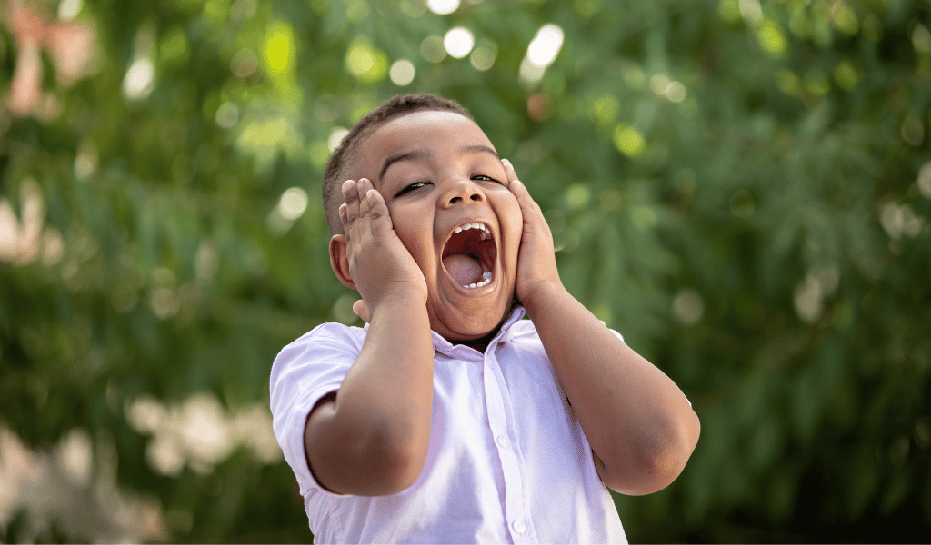 child with high emotions holding his face in an outdoor setting
