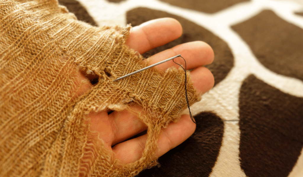 person mending a hole in a sock