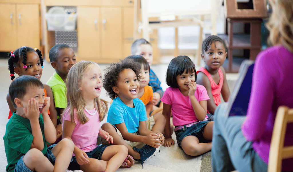 childminder at nursery reading a group of children